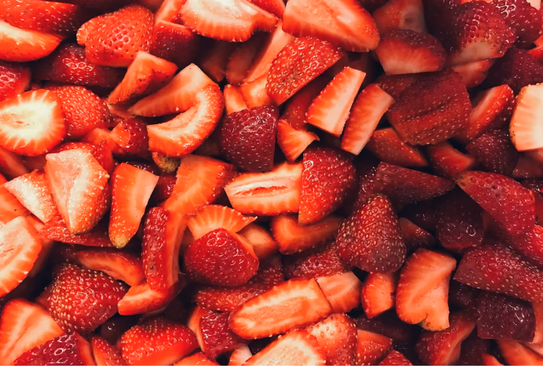 Close-up of fresh red strawberries cut into halves and slices.