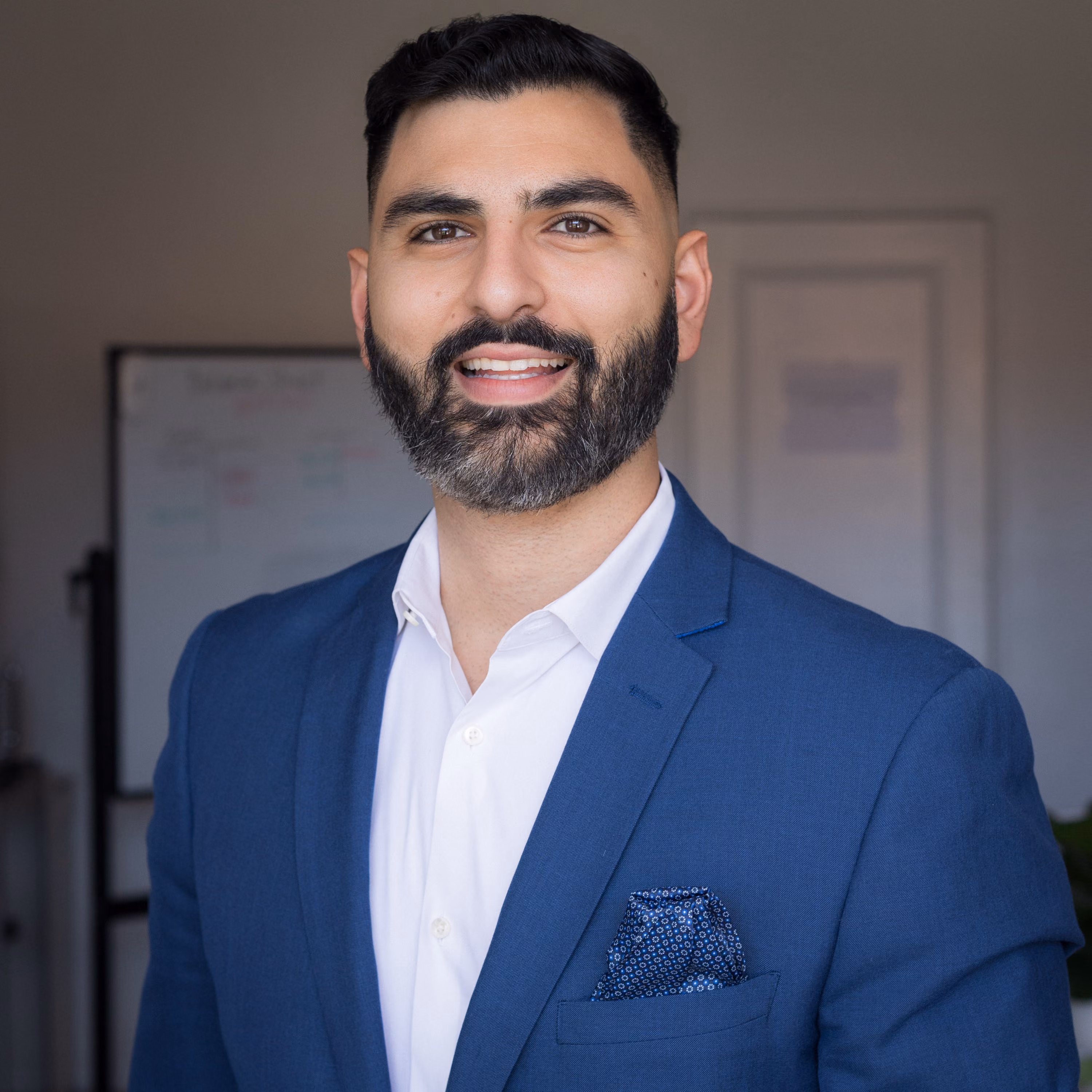 Portrait of Edmond Petrosyan, founder of Athena Tax & Advisory, smiling with arms crossed in a blue suit