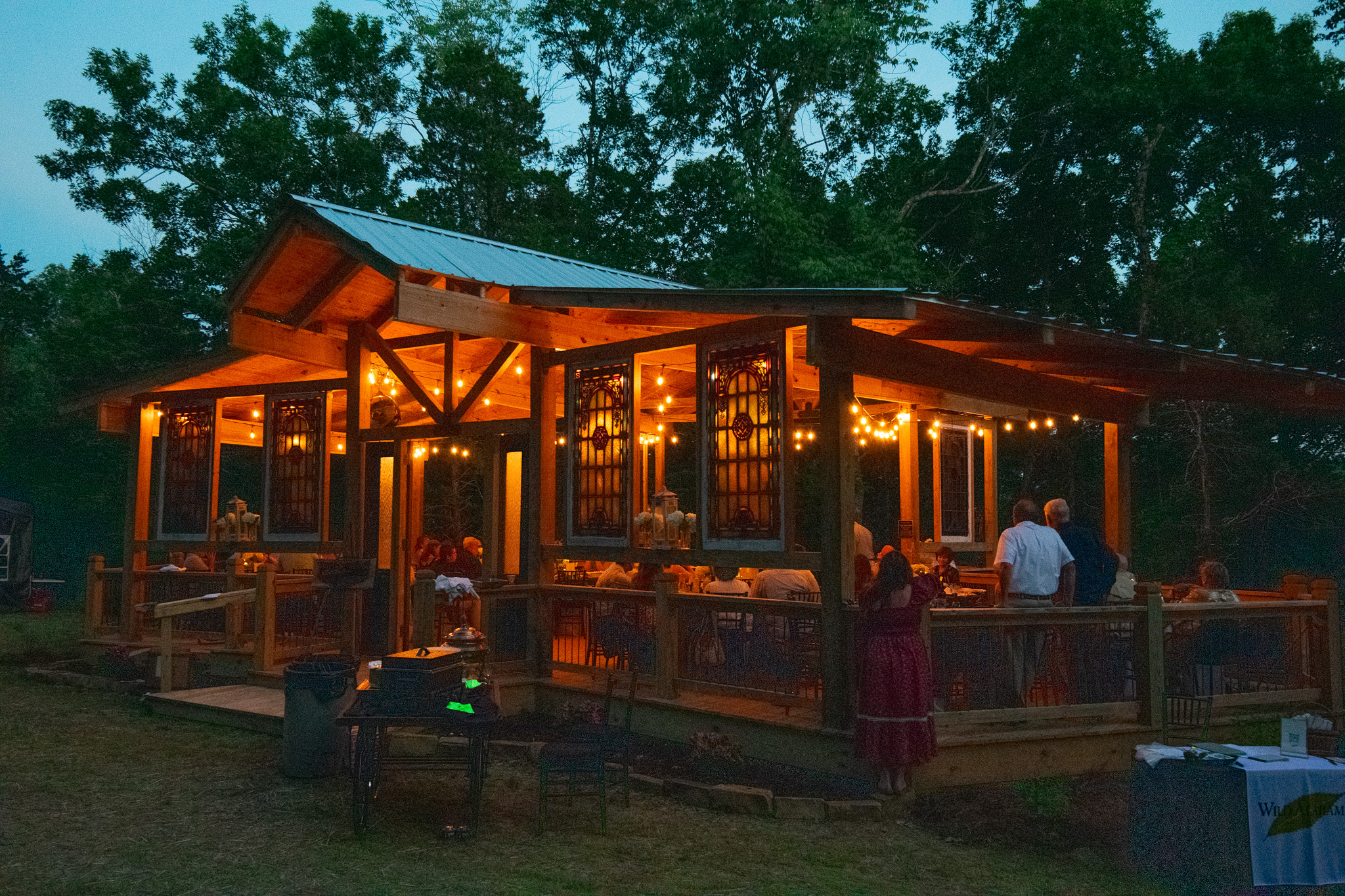 Guests gathering in Ravenwood’s illuminated pavilion during an evening family reunion