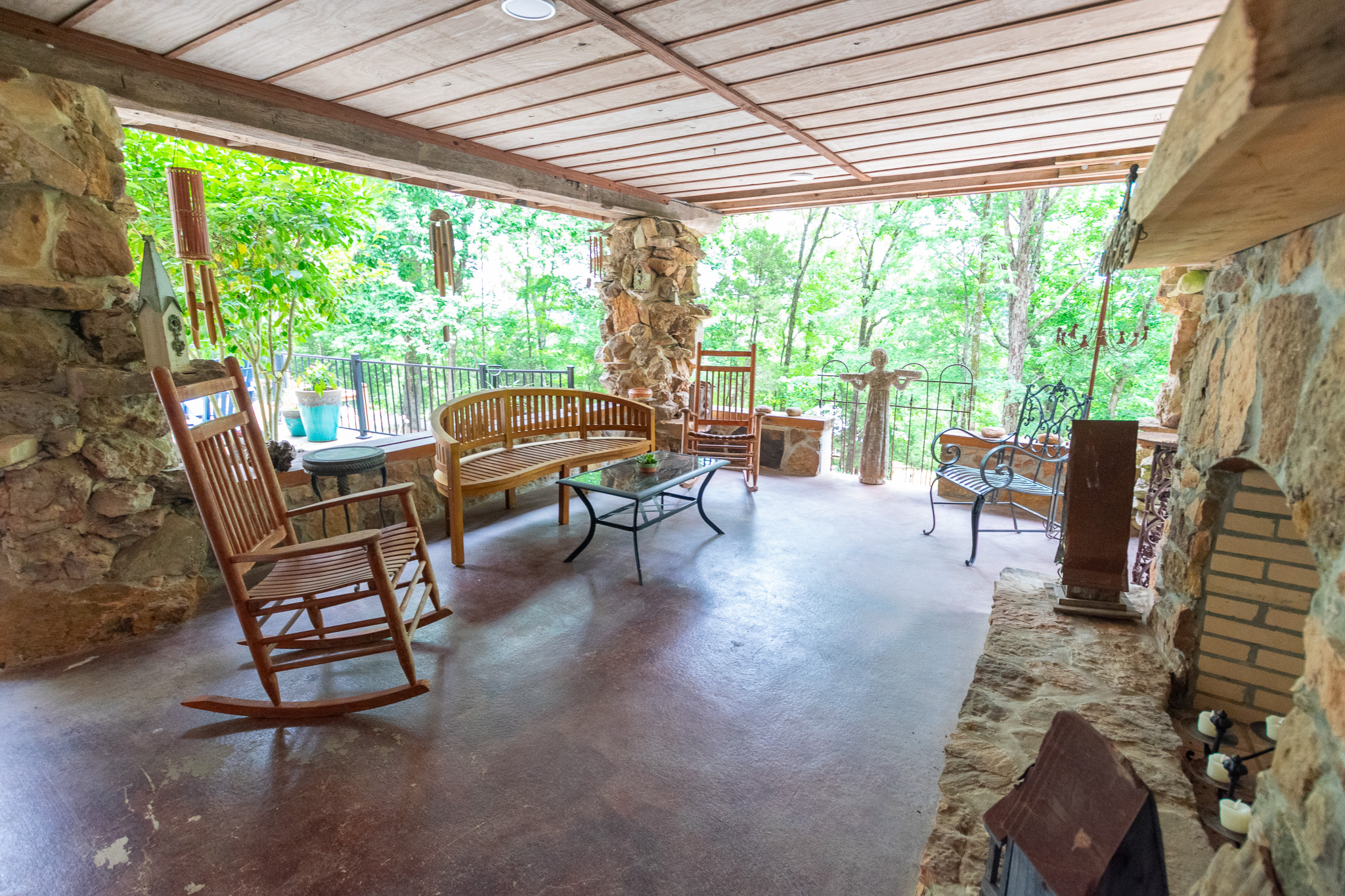 Covered stone porch with rocking chairs overlooking the woods at Ravenwood