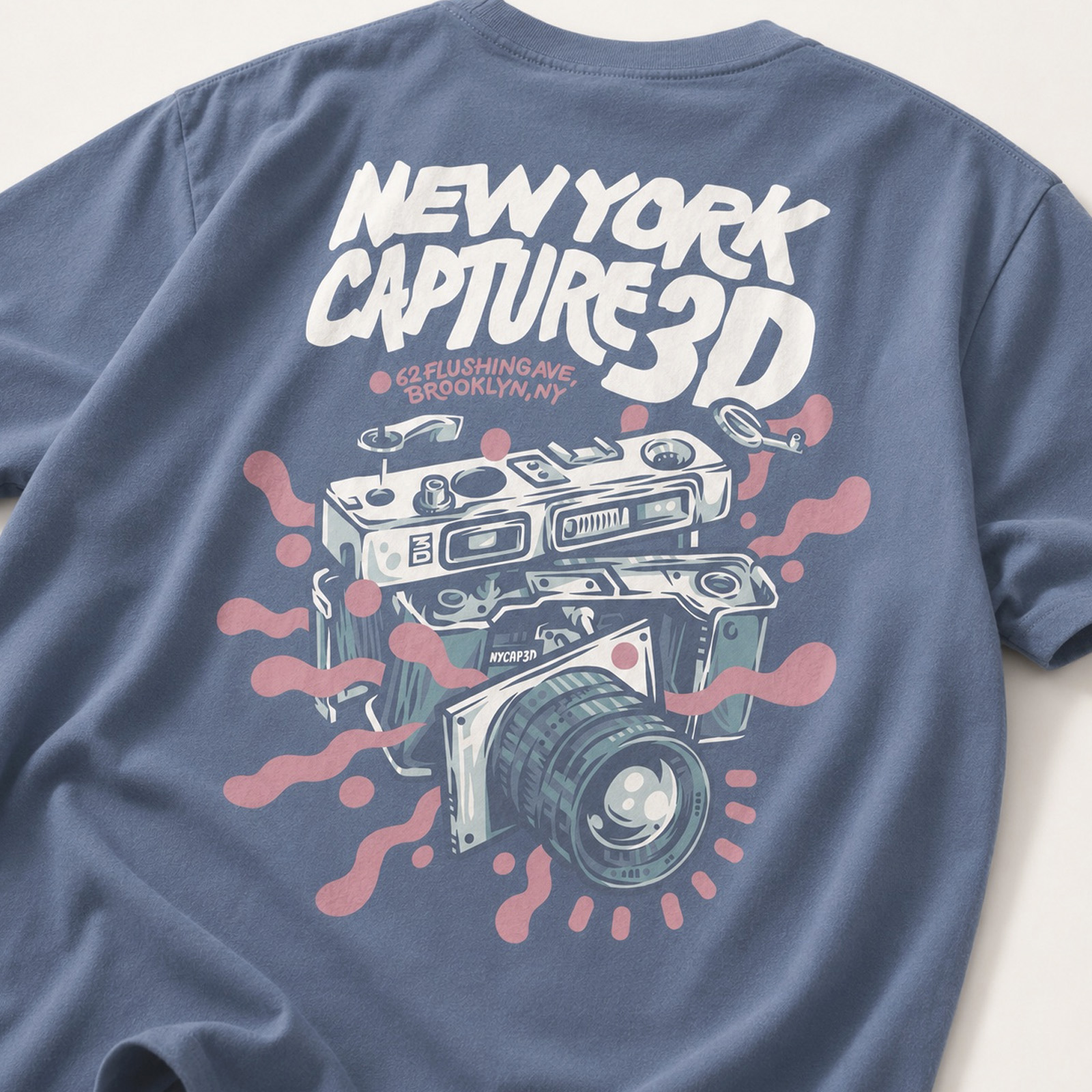 Blue NYCAP3D T-shirt featuring illustrated vintage cameras and bold custom New York Capture 3D typography on the back.