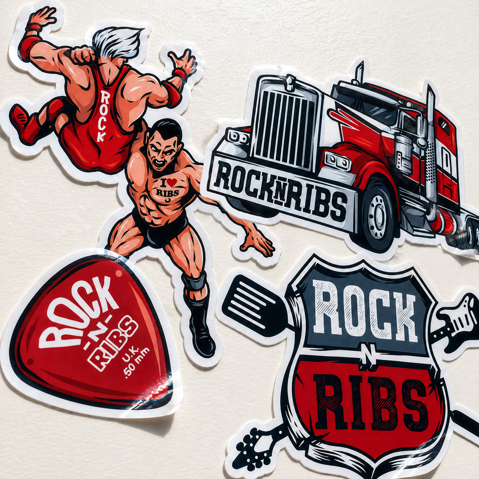 Rock n Ribs printed stickers featuring the festival logo, American truck, guitar pick and illustrated wrestling characters.