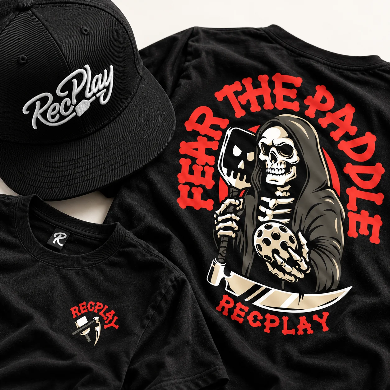 Black RecPLAY cap and T-shirts featuring the RecPLAY logo and Fear the Paddle Grim Reaper artwork.