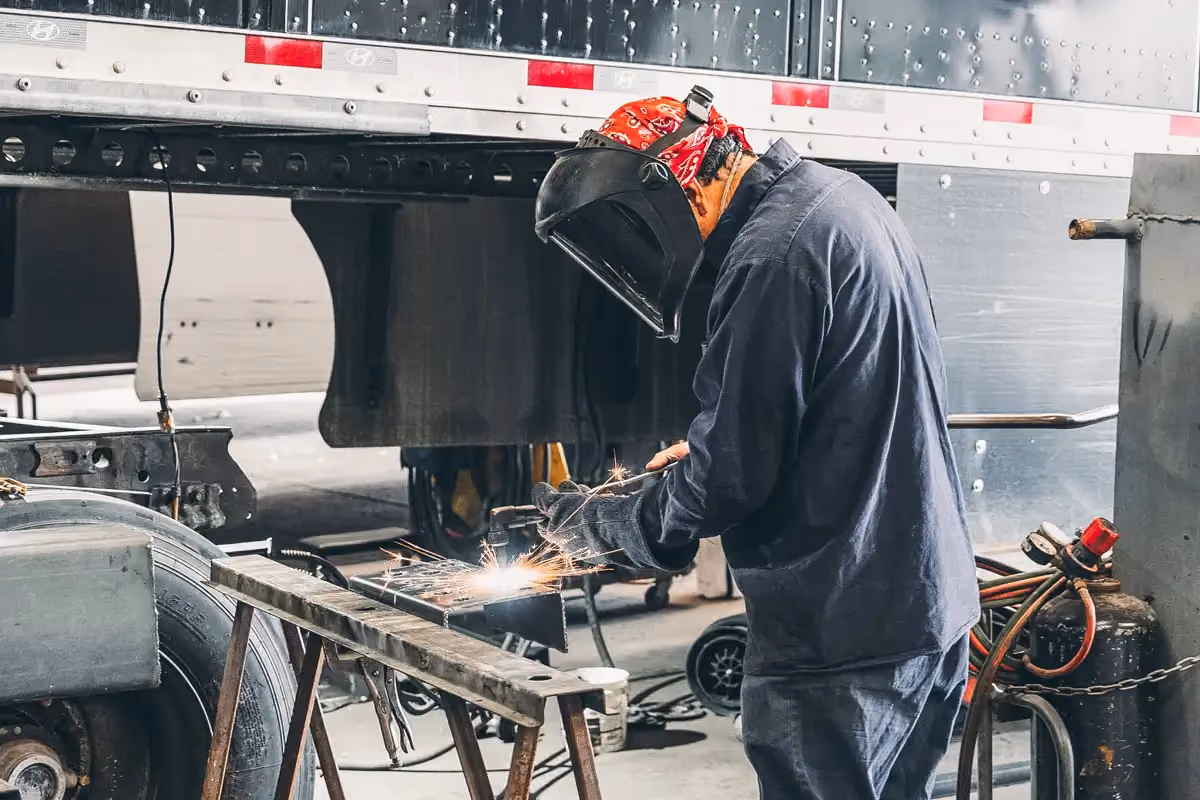 Diesel mechanic performing welding services on body of semi-truck