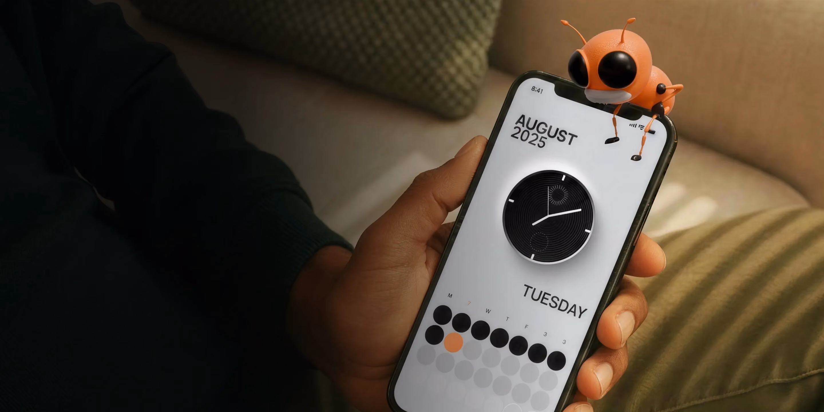 Hand holding phone showing August 2025 Tuesday calendar with a small orange bug on top.