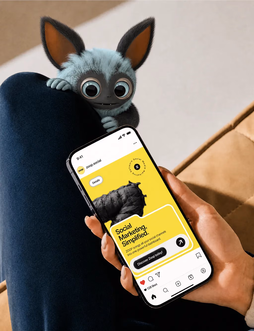 Hand holding phone showing social marketing app; small blue creature with big eyes peeks over knee.