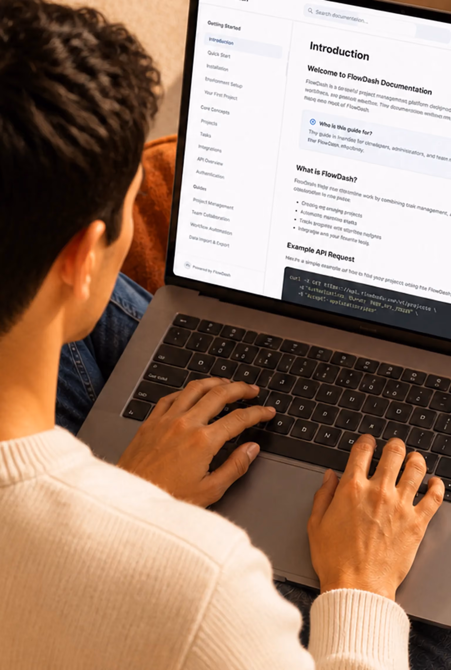Person typing on a laptop showing FlowDash documentation on screen.