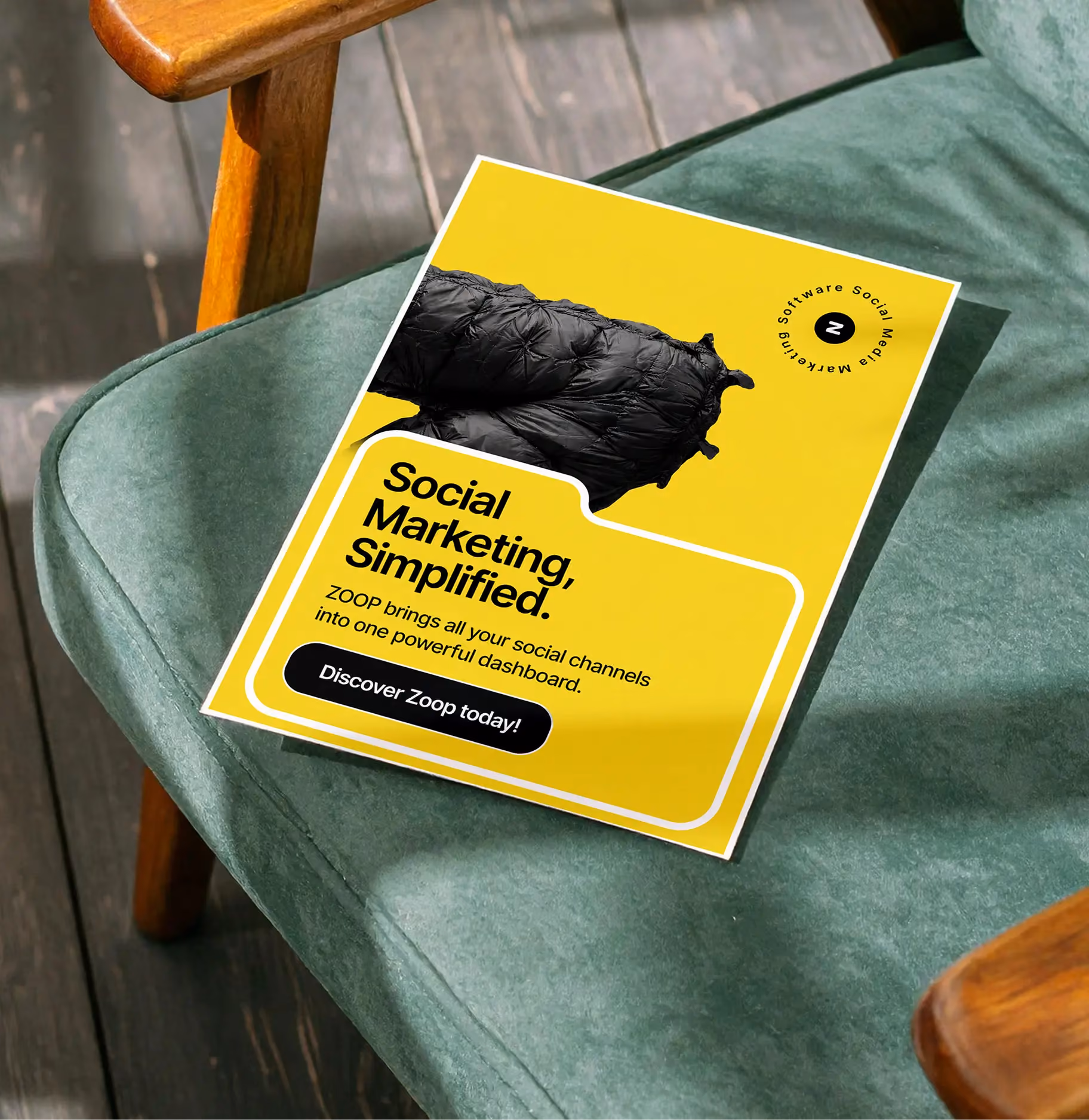 Yellow flyer on green fabric chair advertising Zoop social marketing software dashboard.