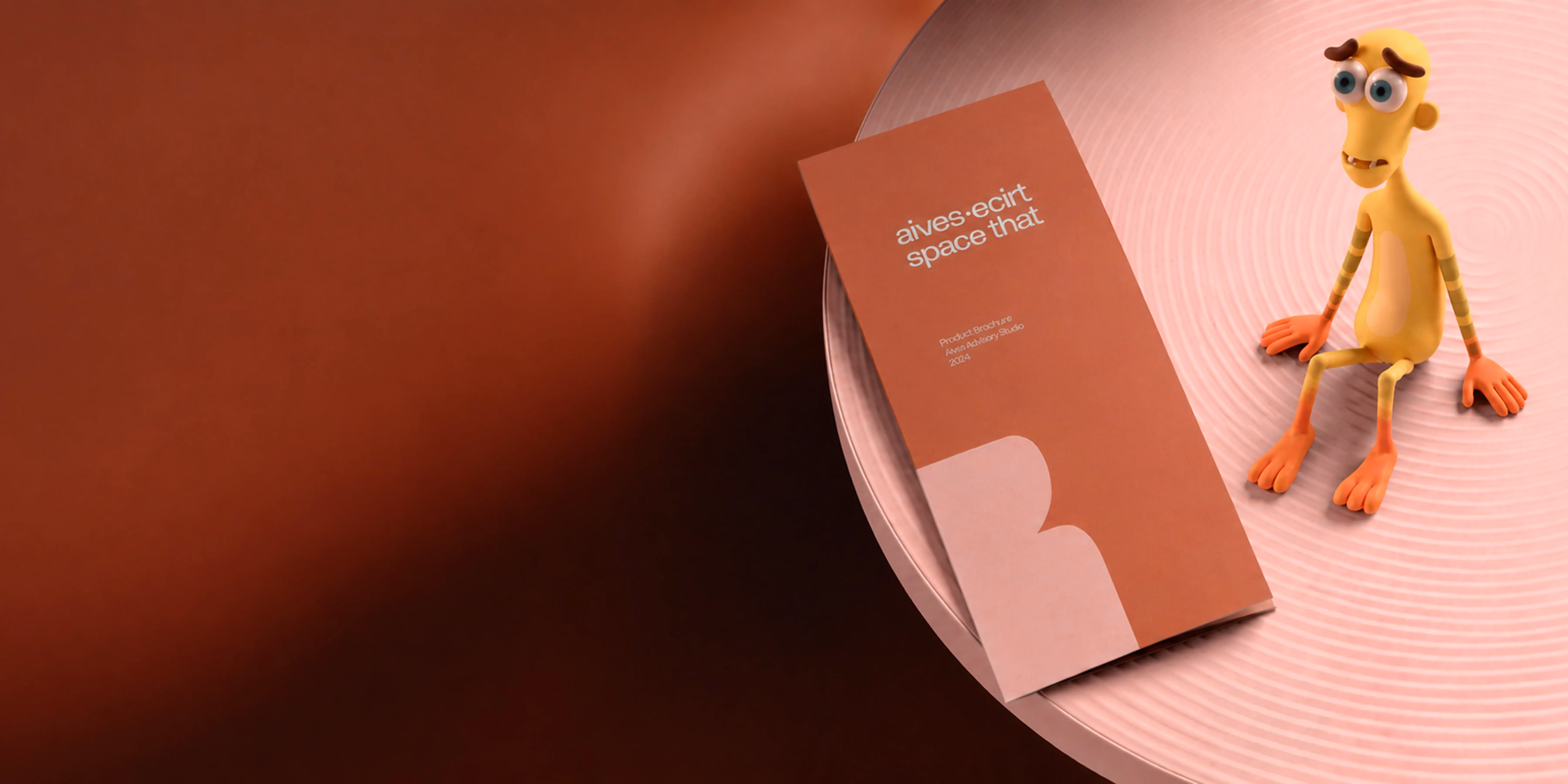 Orange brochure titled 'aives·ecirt space that' on a round pink table with a small yellow cartoon figure.