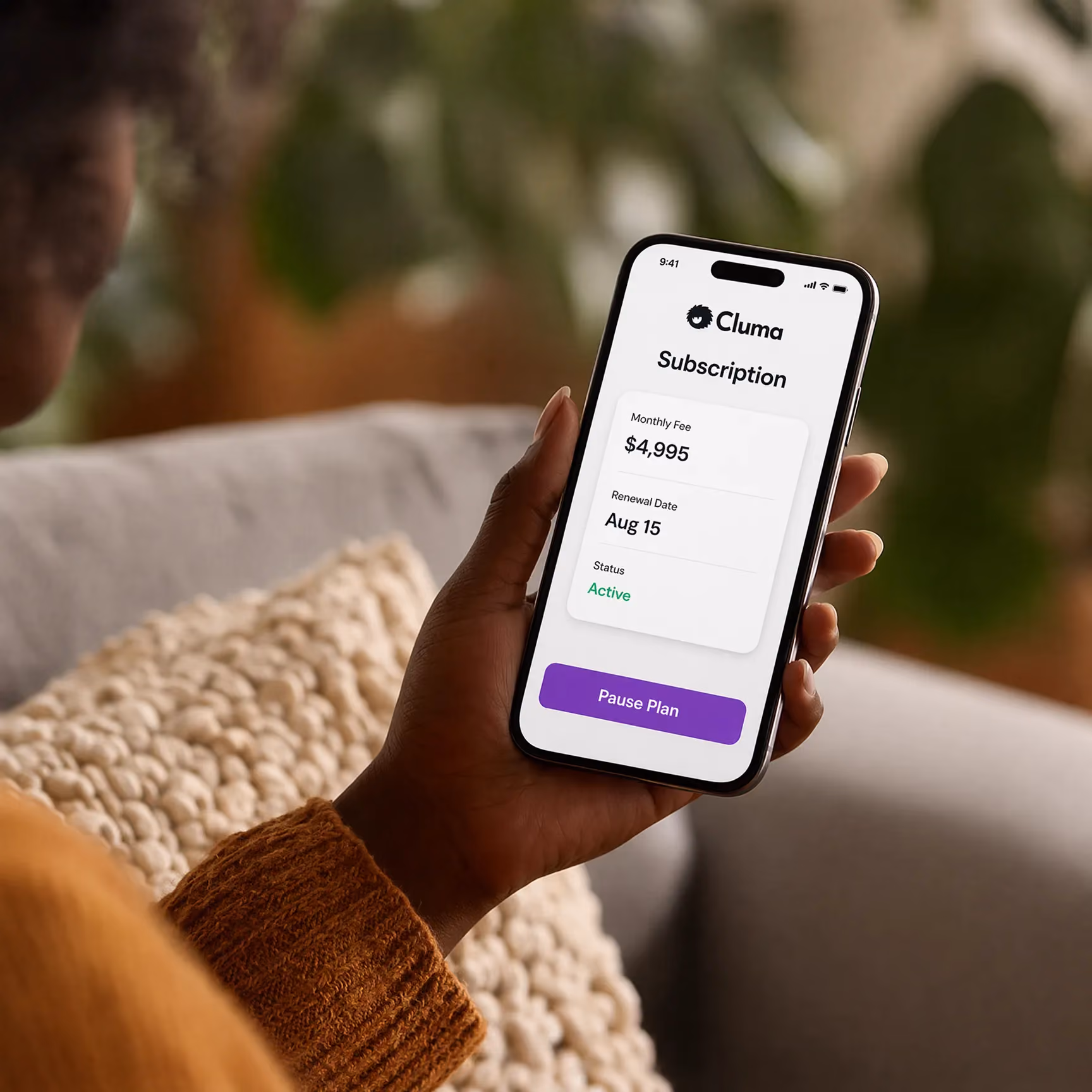 Hand holding a phone showing Cluma subscription with $4,995 fee, renewal Aug 15, active status and pause button.