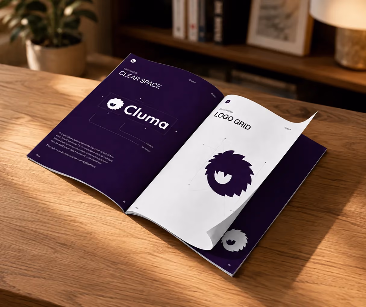 Open booklet on wooden table showing logo design guidelines for 'Cluma' with logo grid and clear space.