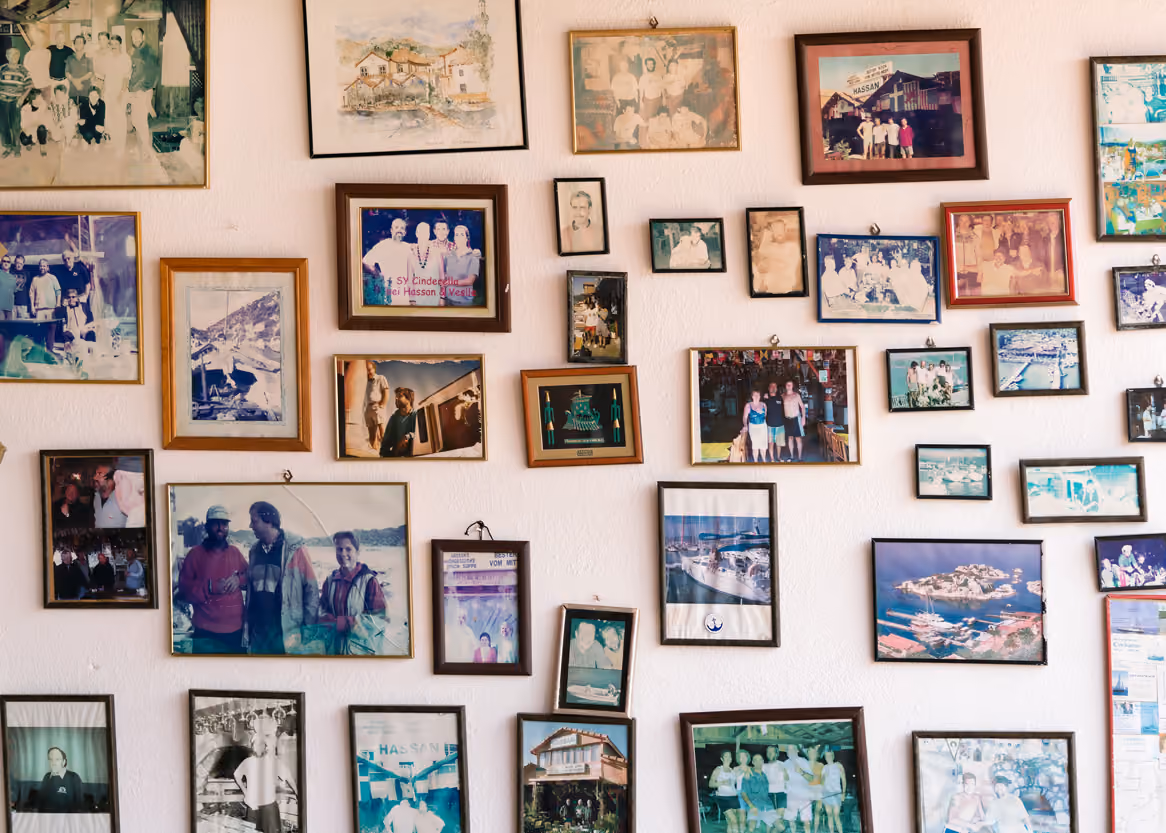 Wall covered with numerous framed photos and paintings of people and landscapes.