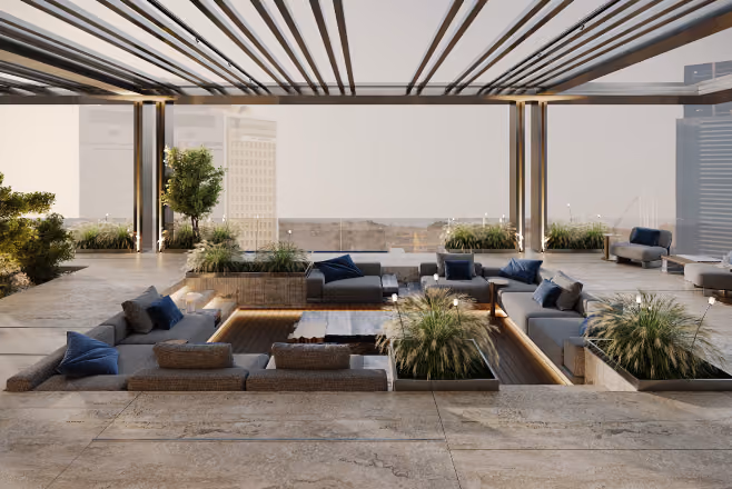 Modern rooftop lounge with sunken seating, blue cushions, plants, and a city view beyond glass walls.