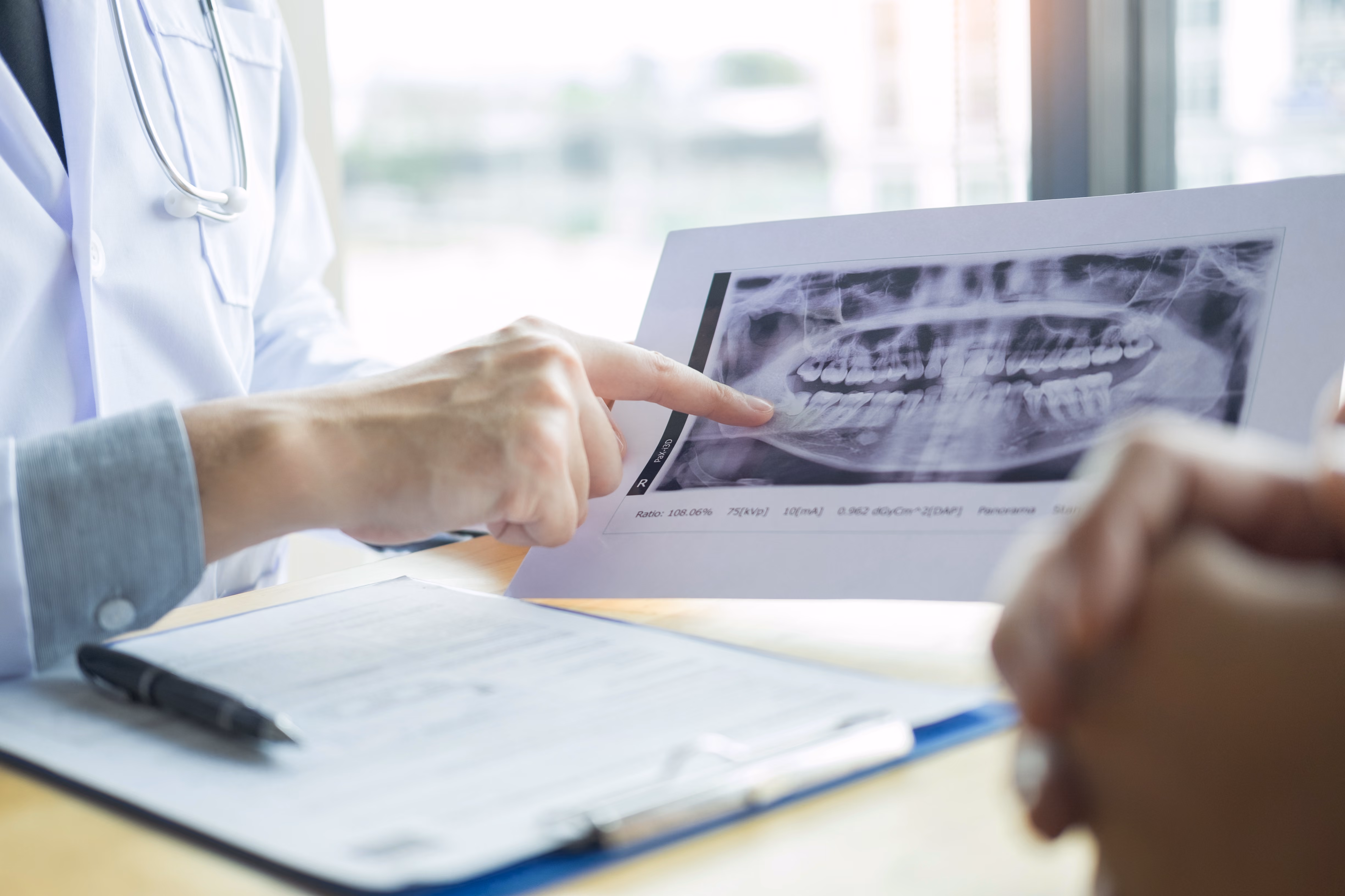 Dentist reviewing a digital dental X-ray showing tooth roots and surrounding bone