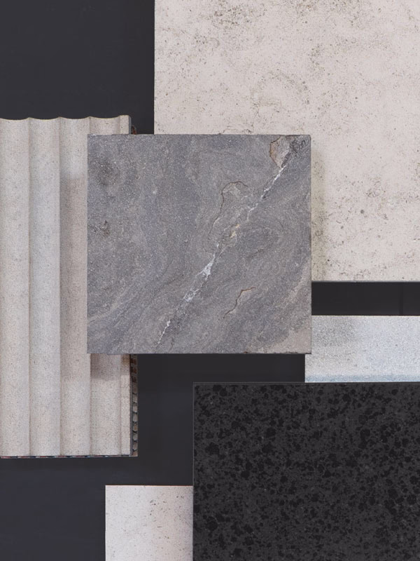 Top view of five stone tiles arranged with varying textures and colors, including smooth black, rough beige, gray stone with a crack, ridged light gray, and smooth light speckled tile on a dark surface.