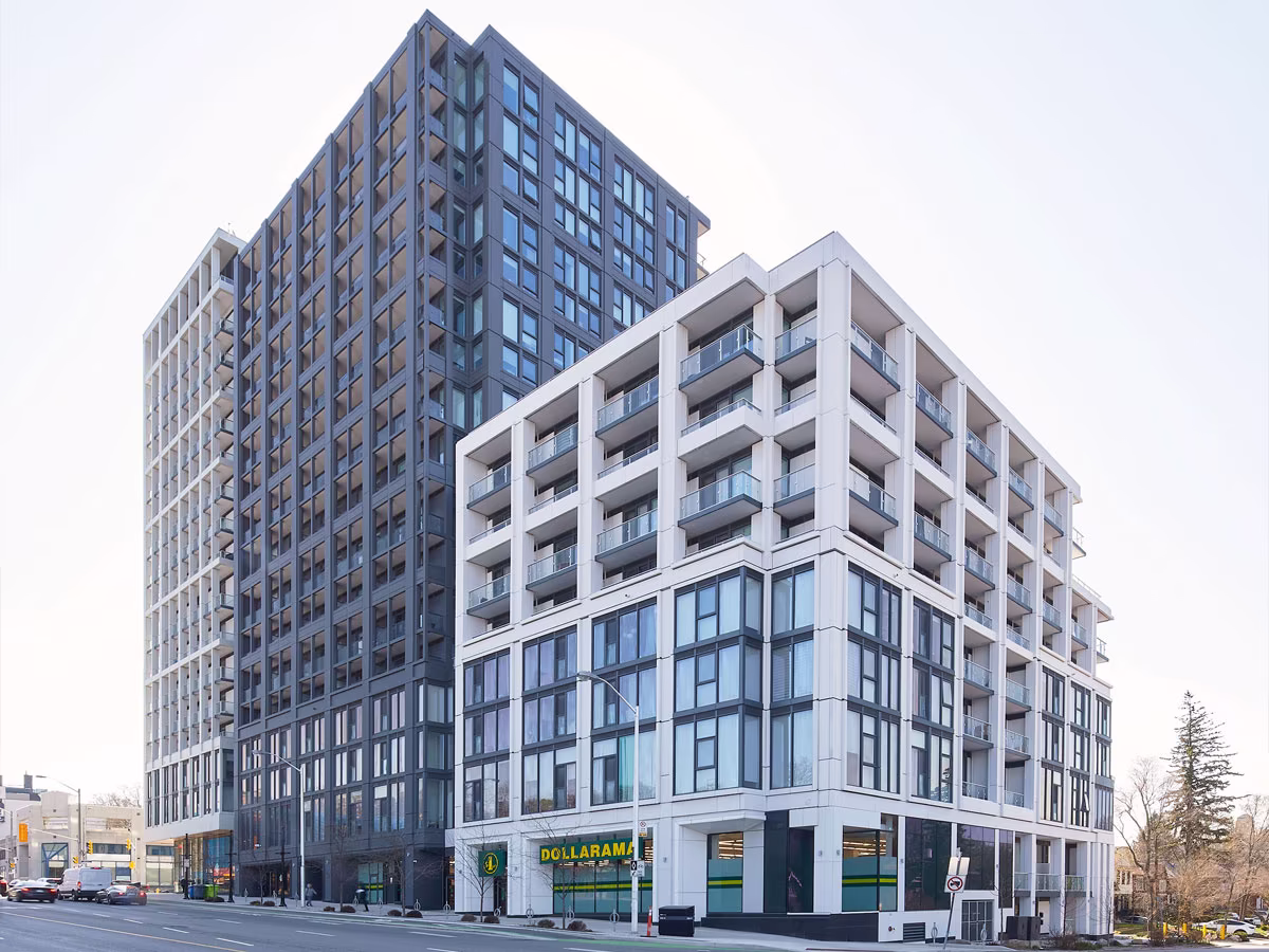 Modern multi-story building complex with a taller dark glass tower and a shorter white building featuring balconies, with a Dollarama store visible on the ground floor.