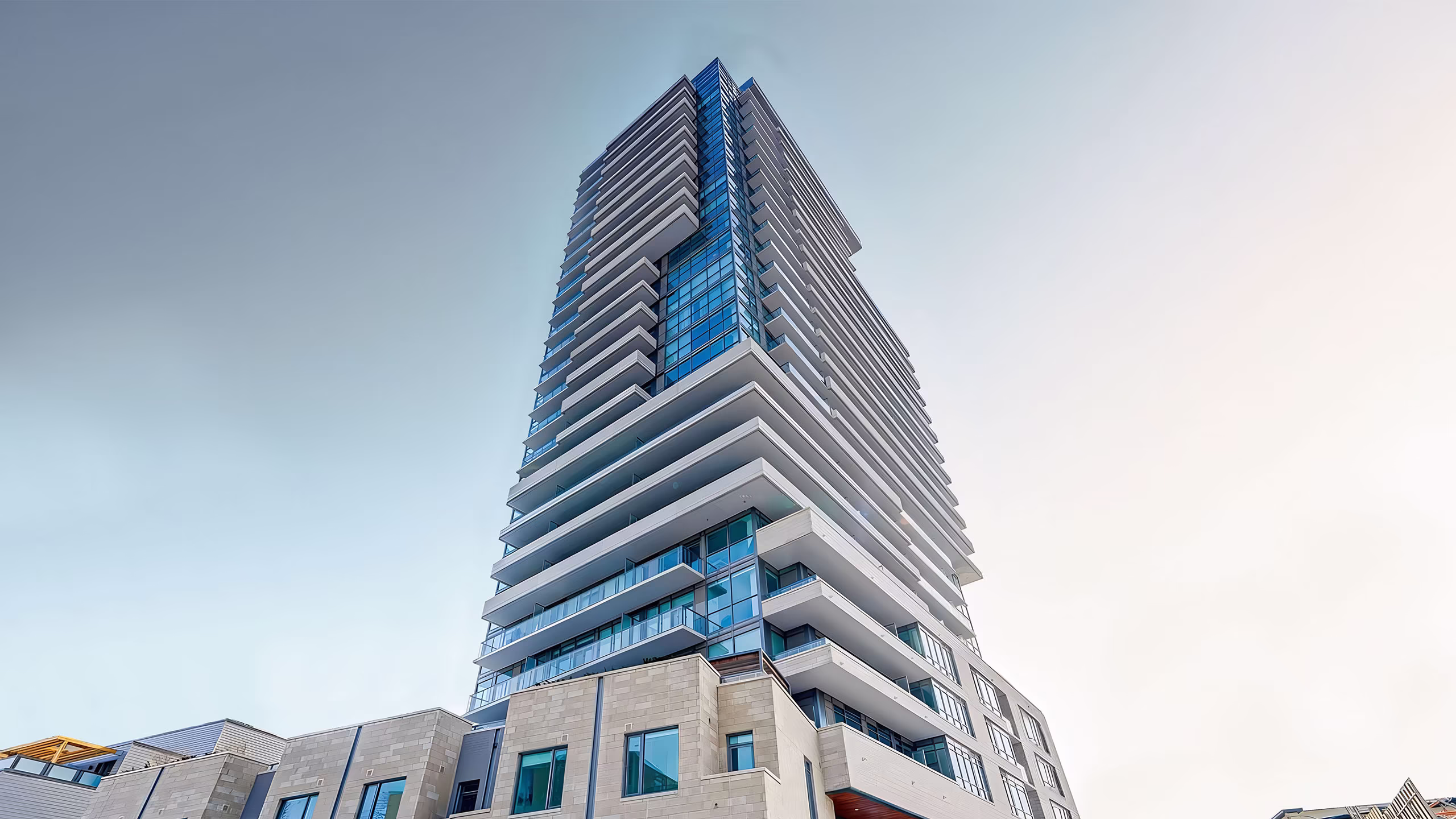 Low-angle view of a modern high-rise building with glass windows and multiple balconies against a clear sky.