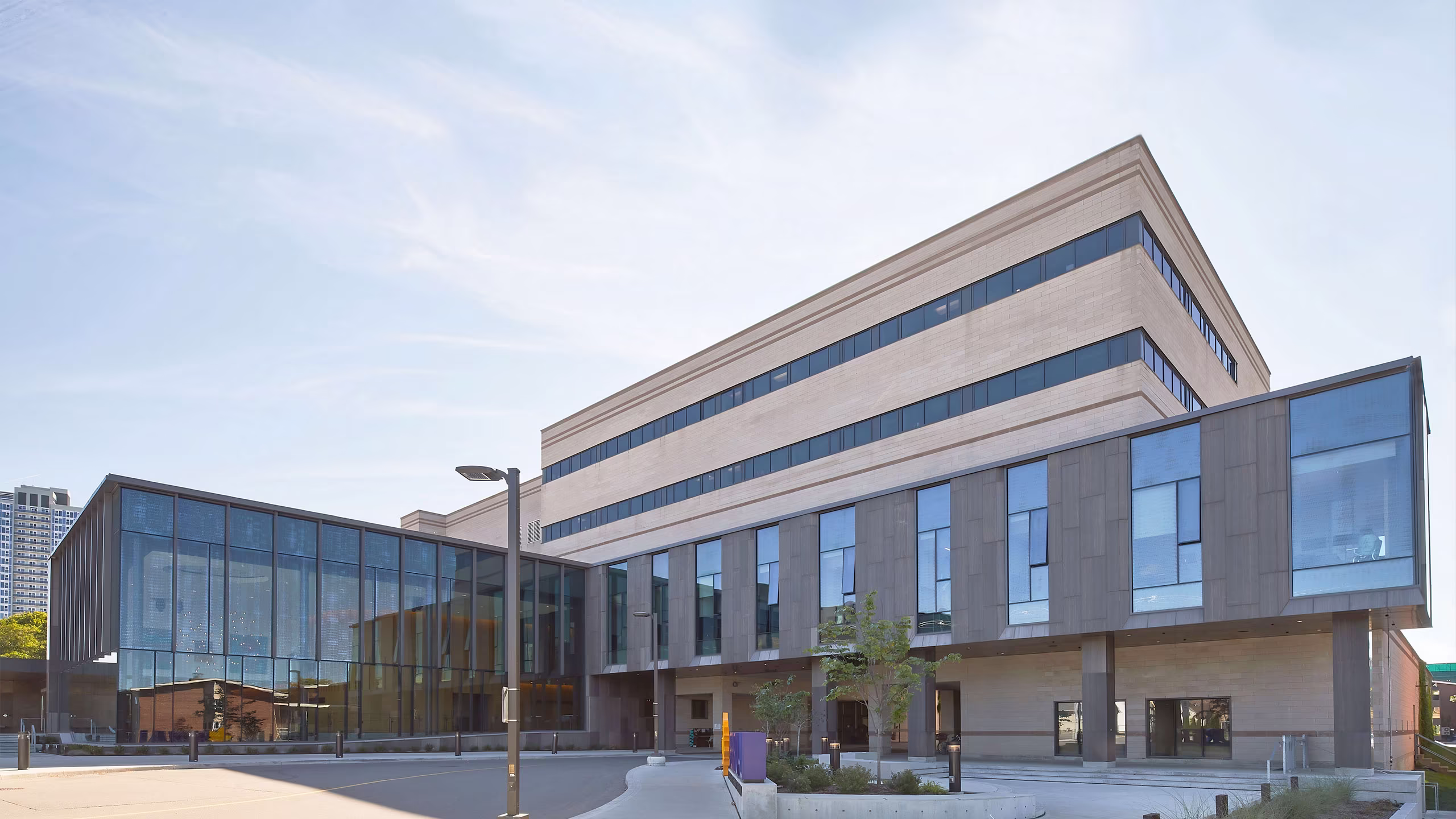 Modern university building with multiple floors featuring large glass windows and a clear sky background.