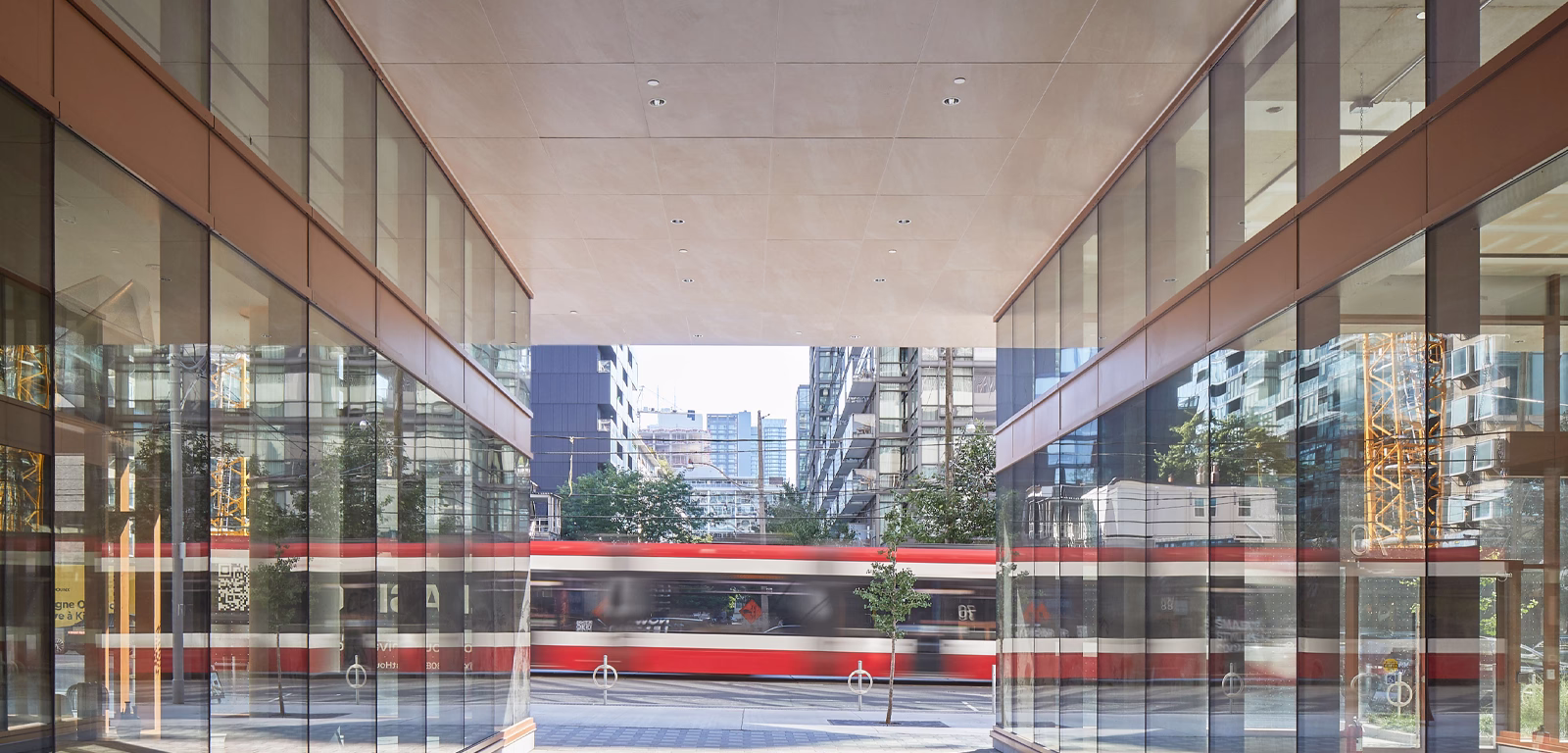 Blurred red and white streetcar moving quickly through a modern urban area framed by glass buildings reflecting city structures.