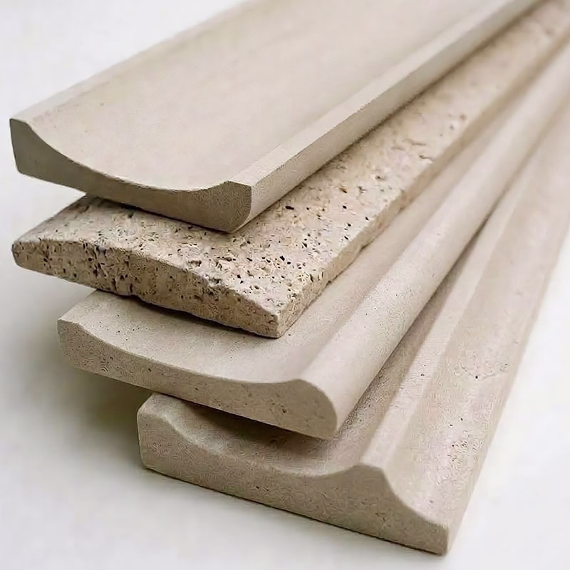 Close-up view of four stacked light beige stone molding pieces, each with different curved and fluted profiles and textured surfaces.
