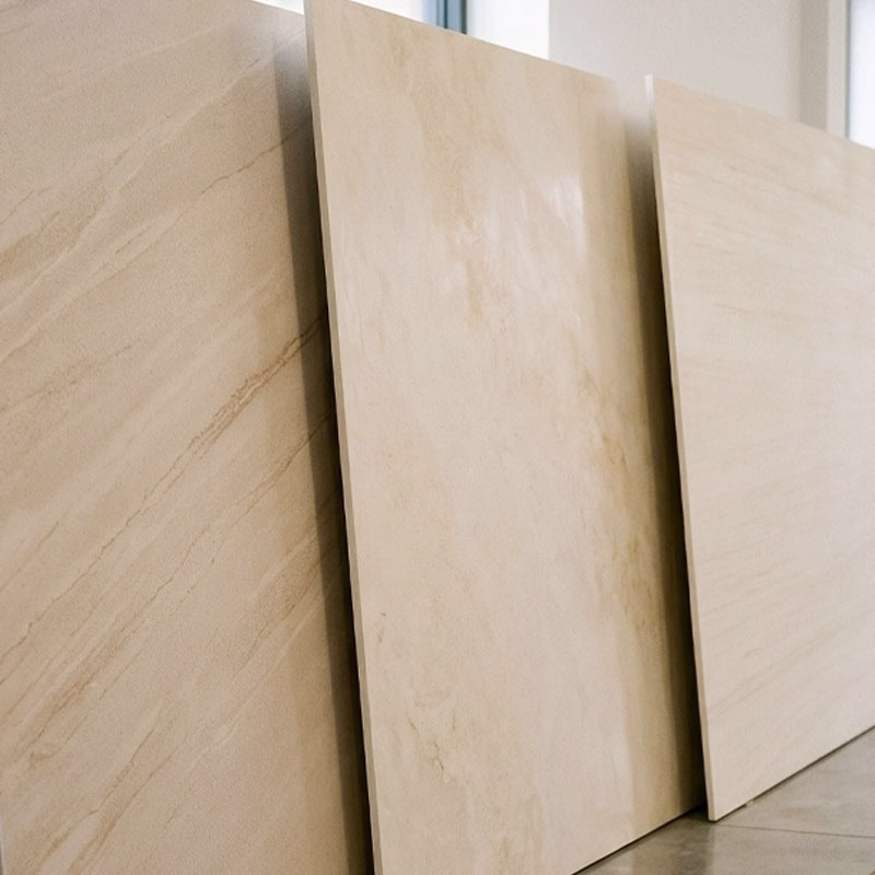 Three large beige porcelain tiles with subtle wood and stone grain patterns, leaning vertically against a wall indoors near windows.