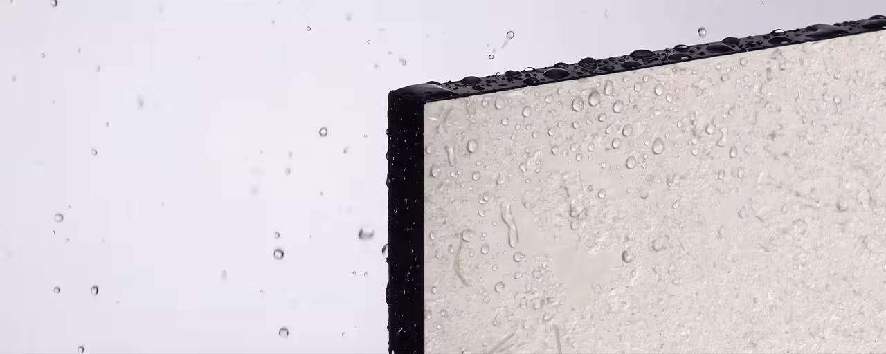 Close-up of water droplets on the surface and black edge of a flat panel against a light background.