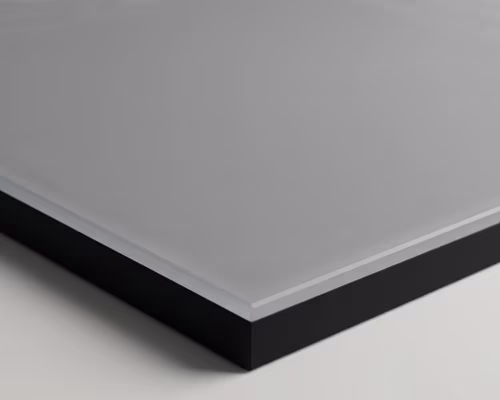 Close-up of a smooth, rectangular solar panel surface with a gray top and black edge on a light background.