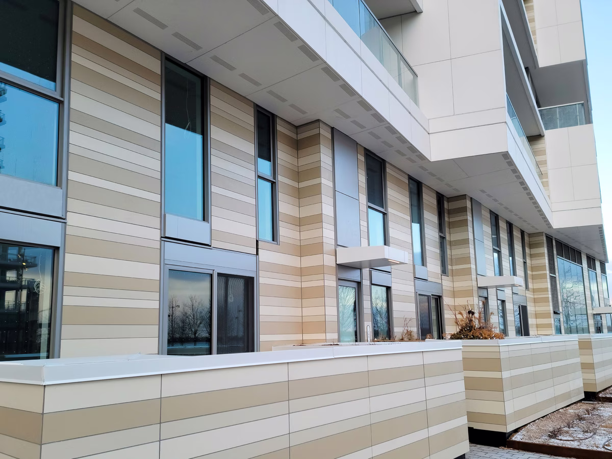 Modern building exterior featuring horizontal beige and tan paneling with tall vertical windows and balconies.
