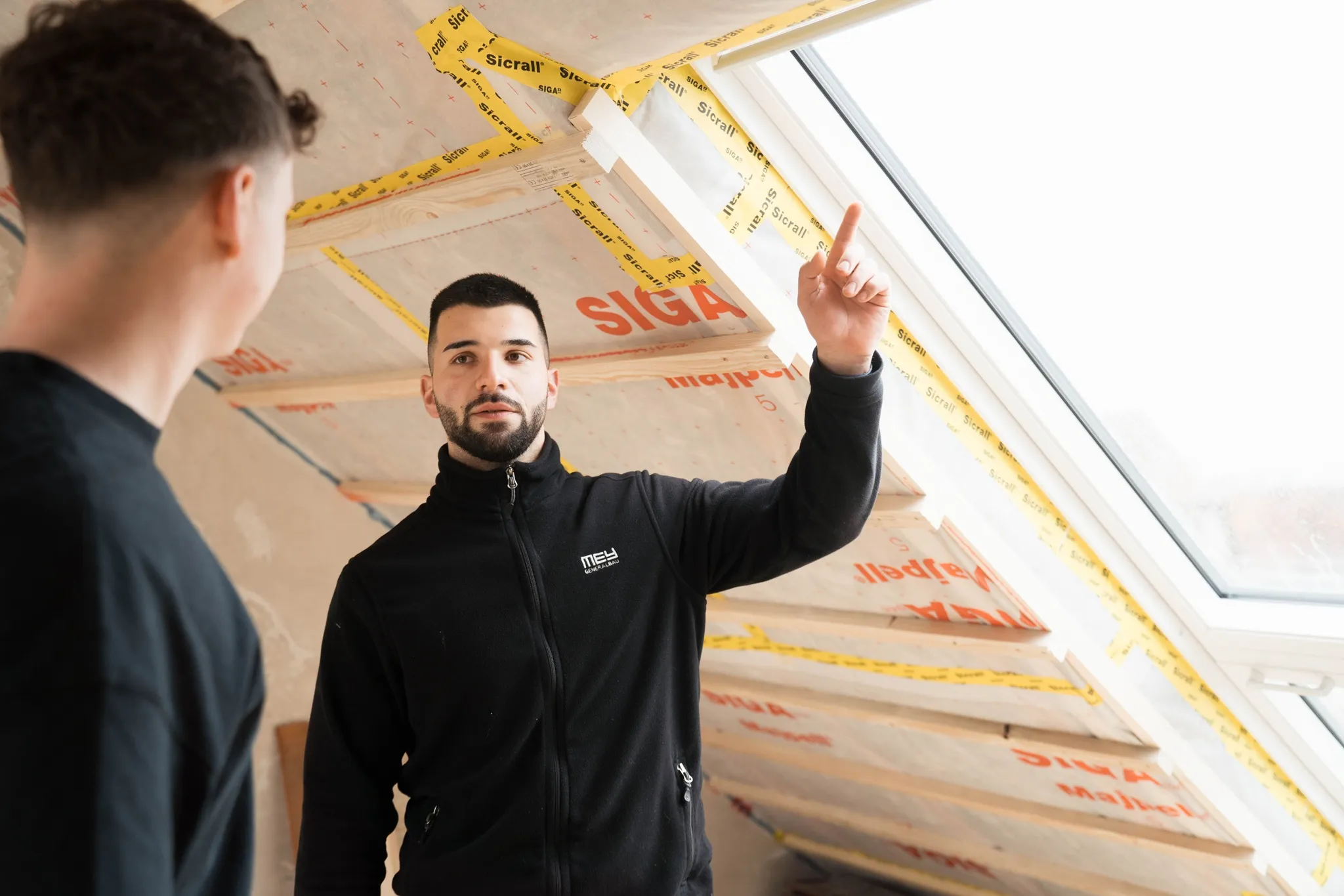 Zwei Mitarbeiter besprechen einen Dachausbau