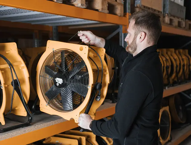 Techniker im Lager mit Bautrocknern und Ventilatoren