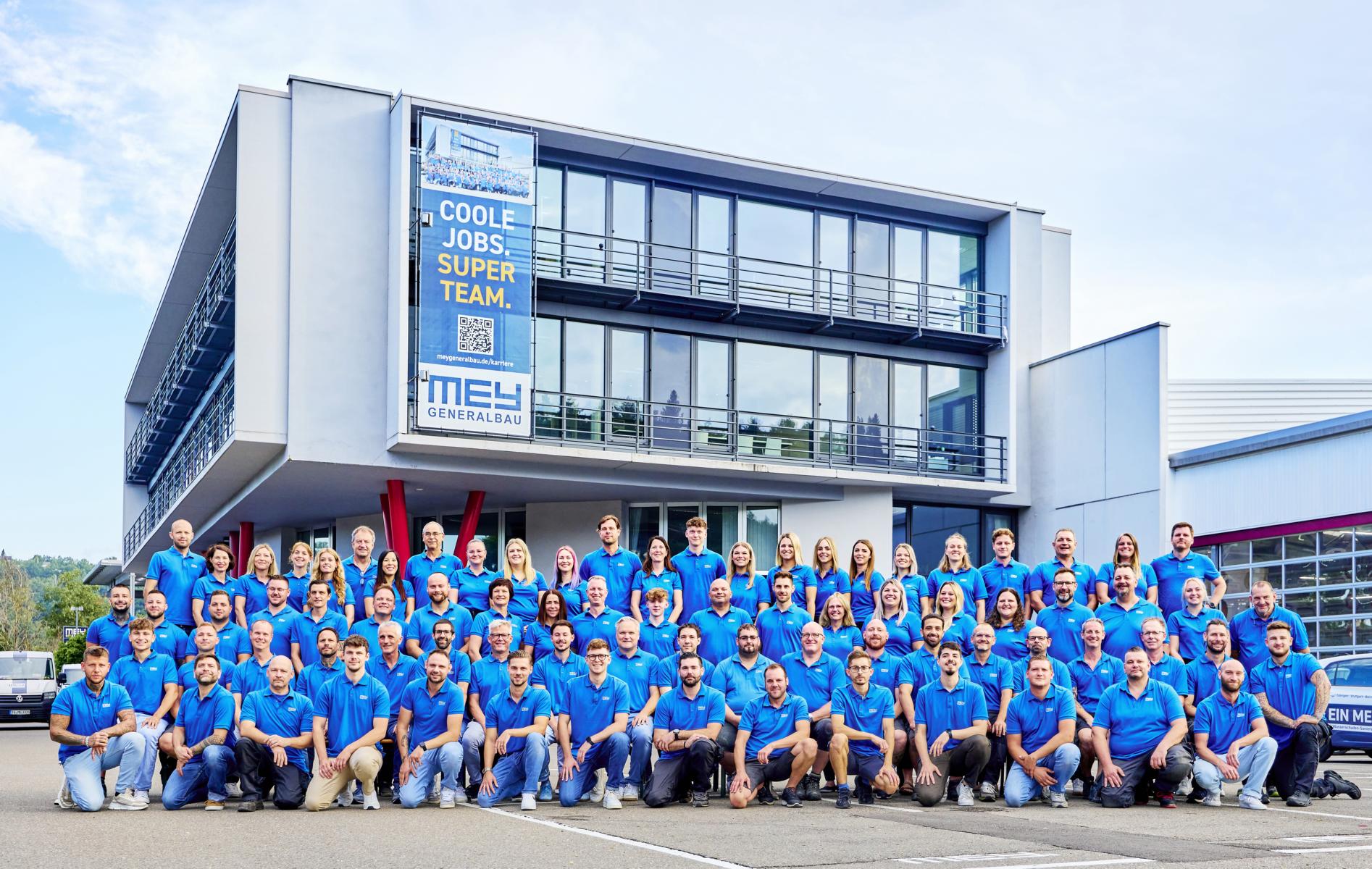 Gruppenfoto des Mey-Teams vor dem Firmengebäude