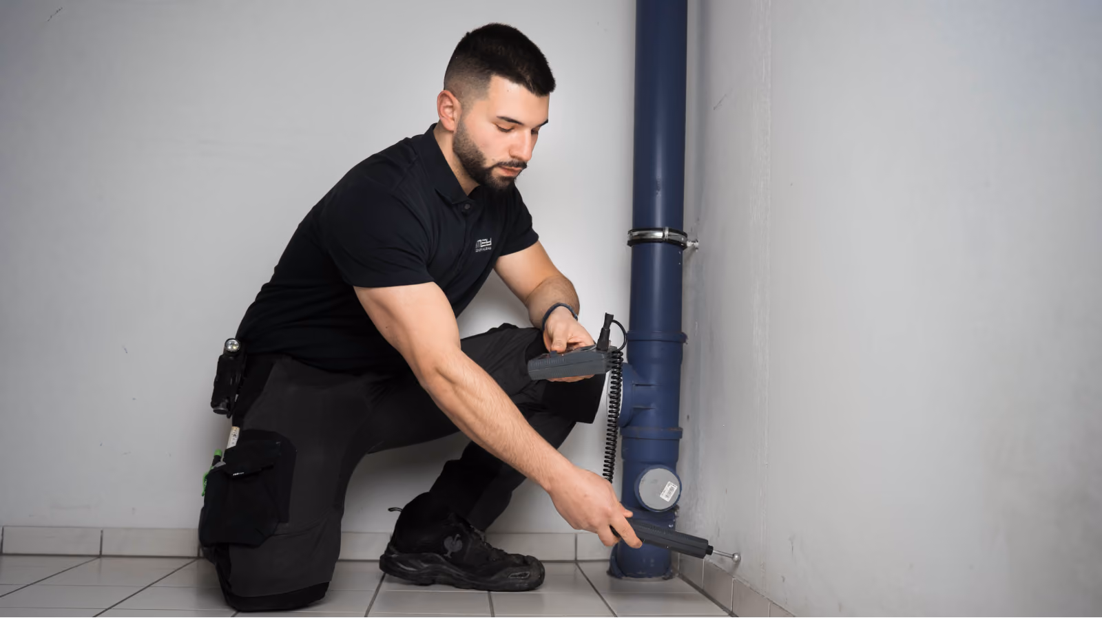 Techniker kniet bei der Leckortung an einer Leitung