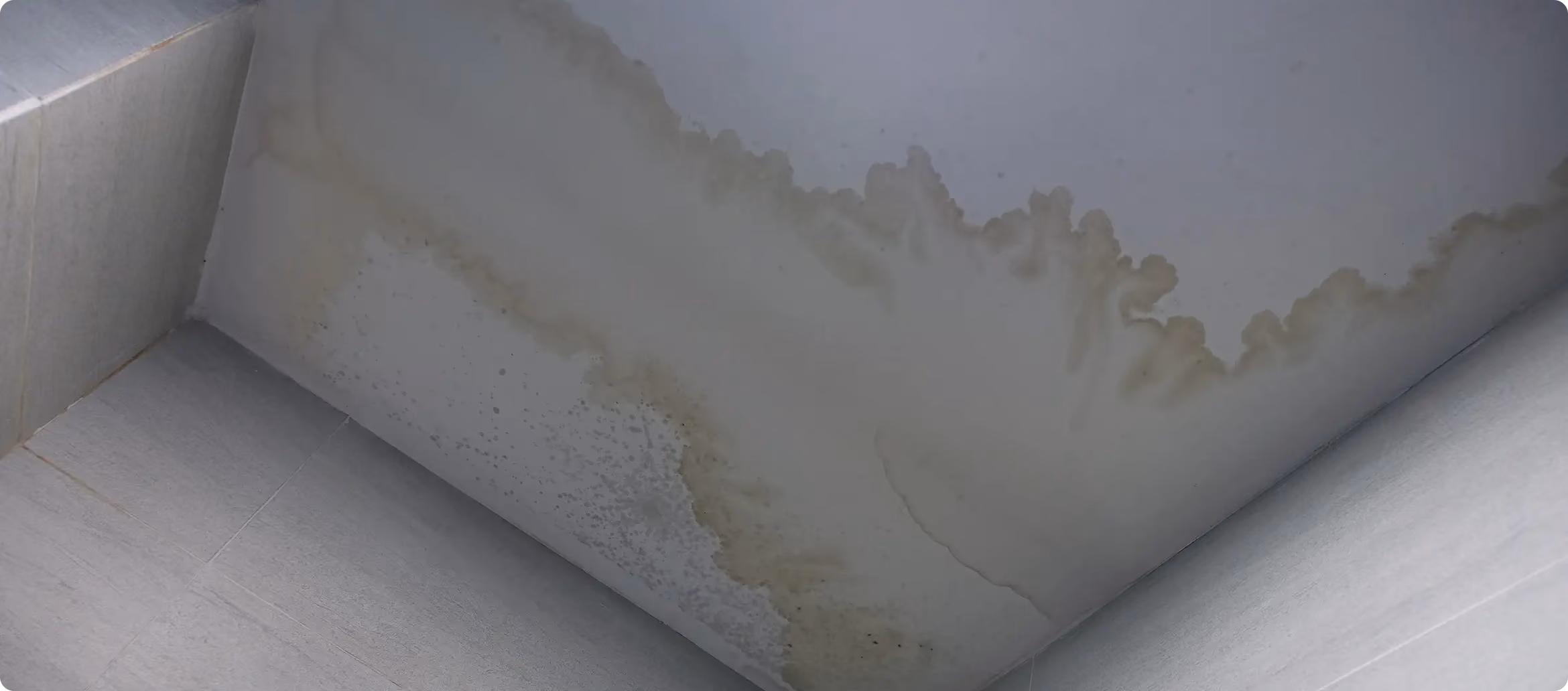 Feuchte Wand mit dunklen Flecken und abplatzender Farbe
