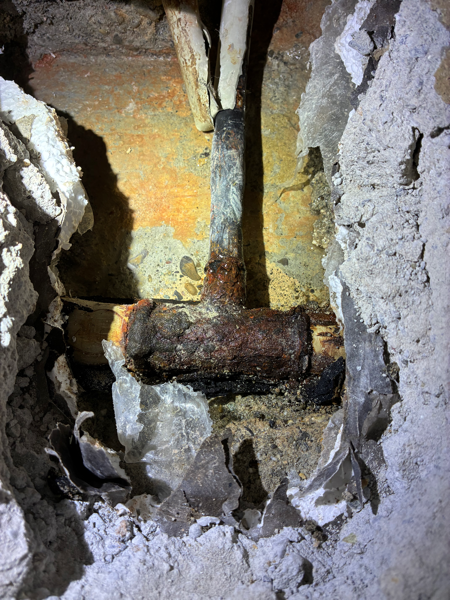 Freigelegtes, korrodiertes Heizungsrohr in der geöffneten Wand