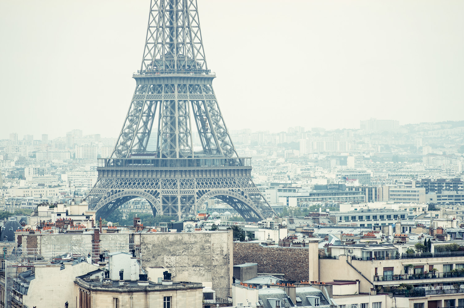 Eiffelturm über Paris' Stadtlandschaft an einem leicht nebligen Tag.