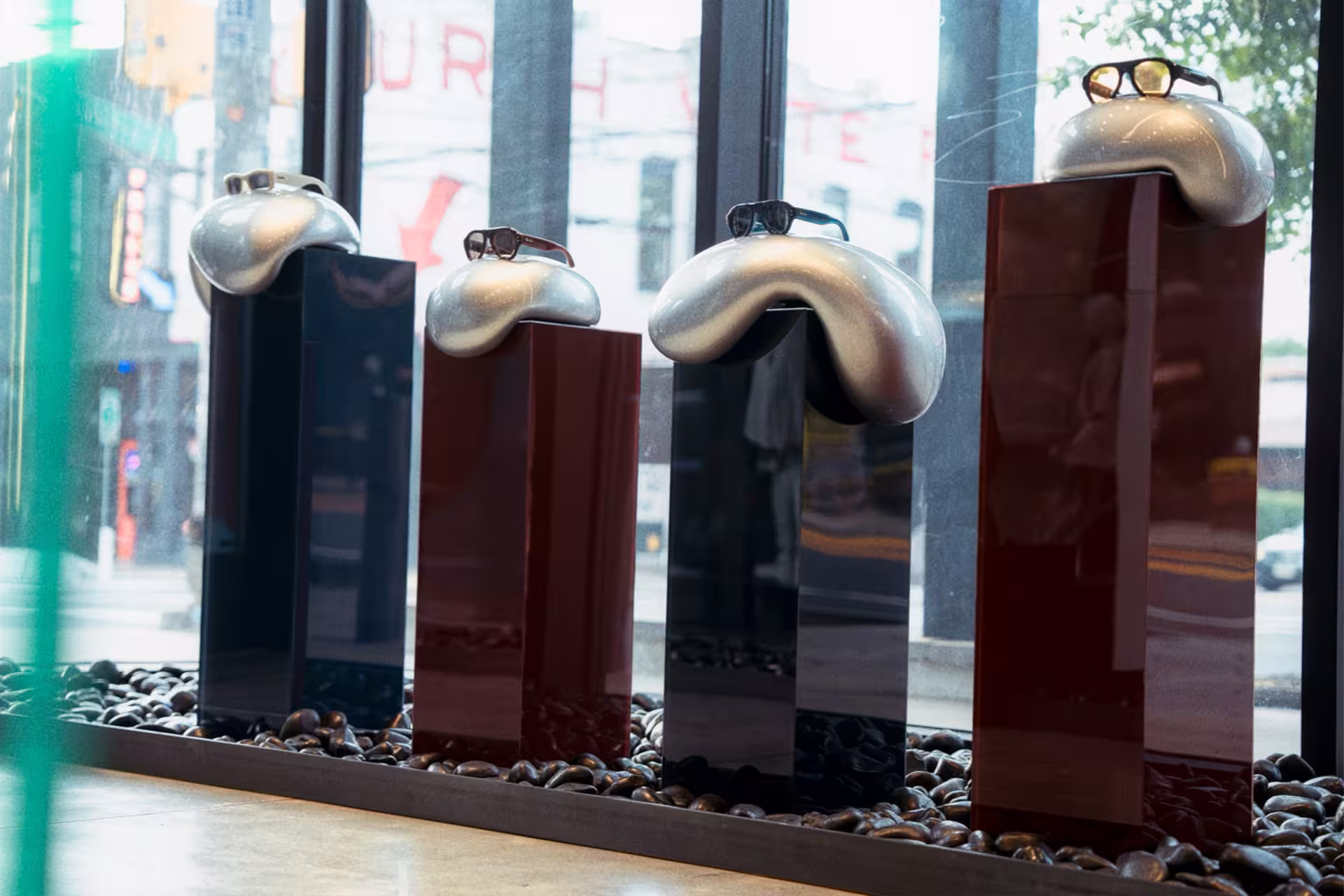 four plinths in metallic with puffer displays holding ray-ban frames beneath red neon sign that says ray-ban