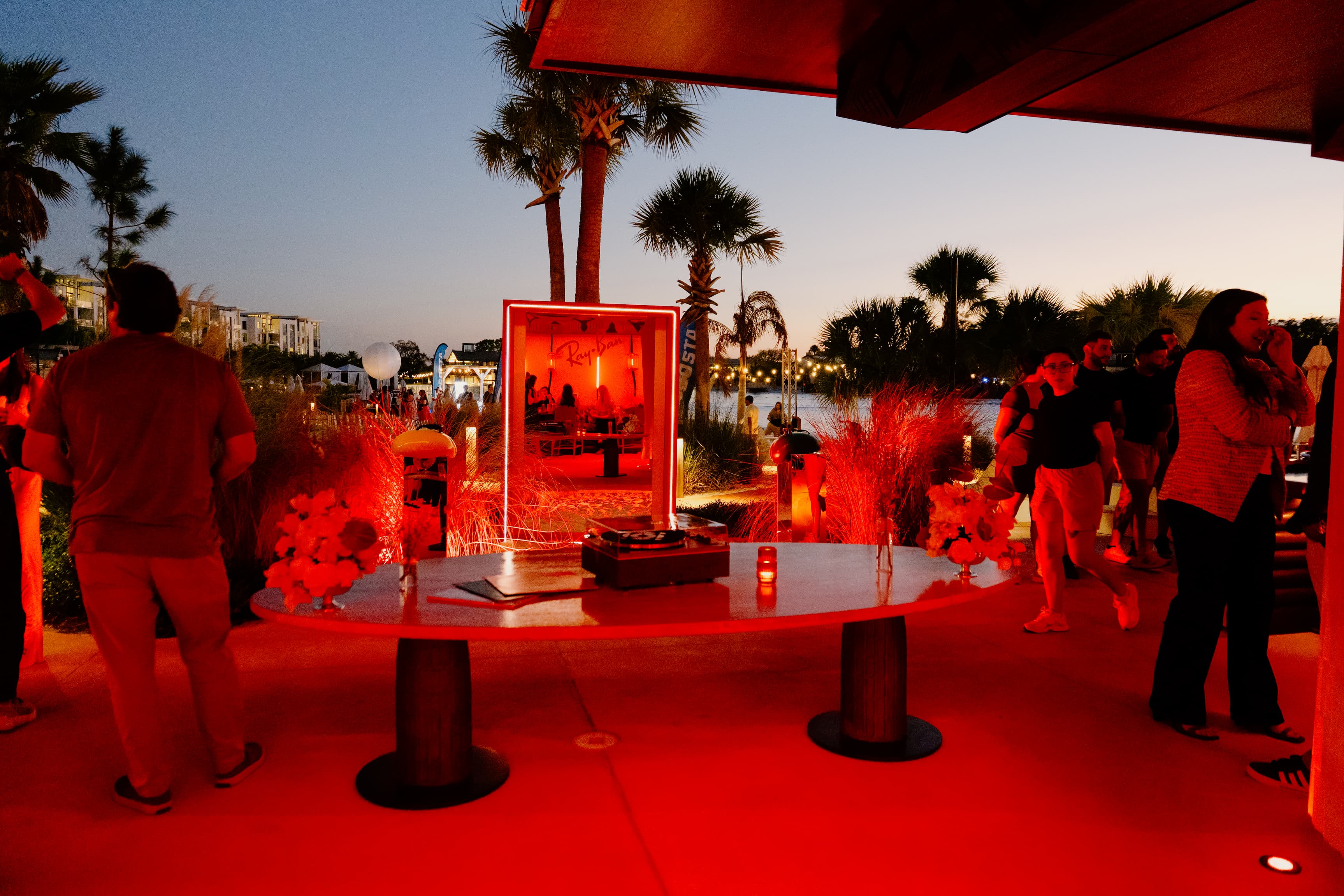 Conrad hotel bar patio featuring illuminated ray-ban signs and guests mingling around at dusk