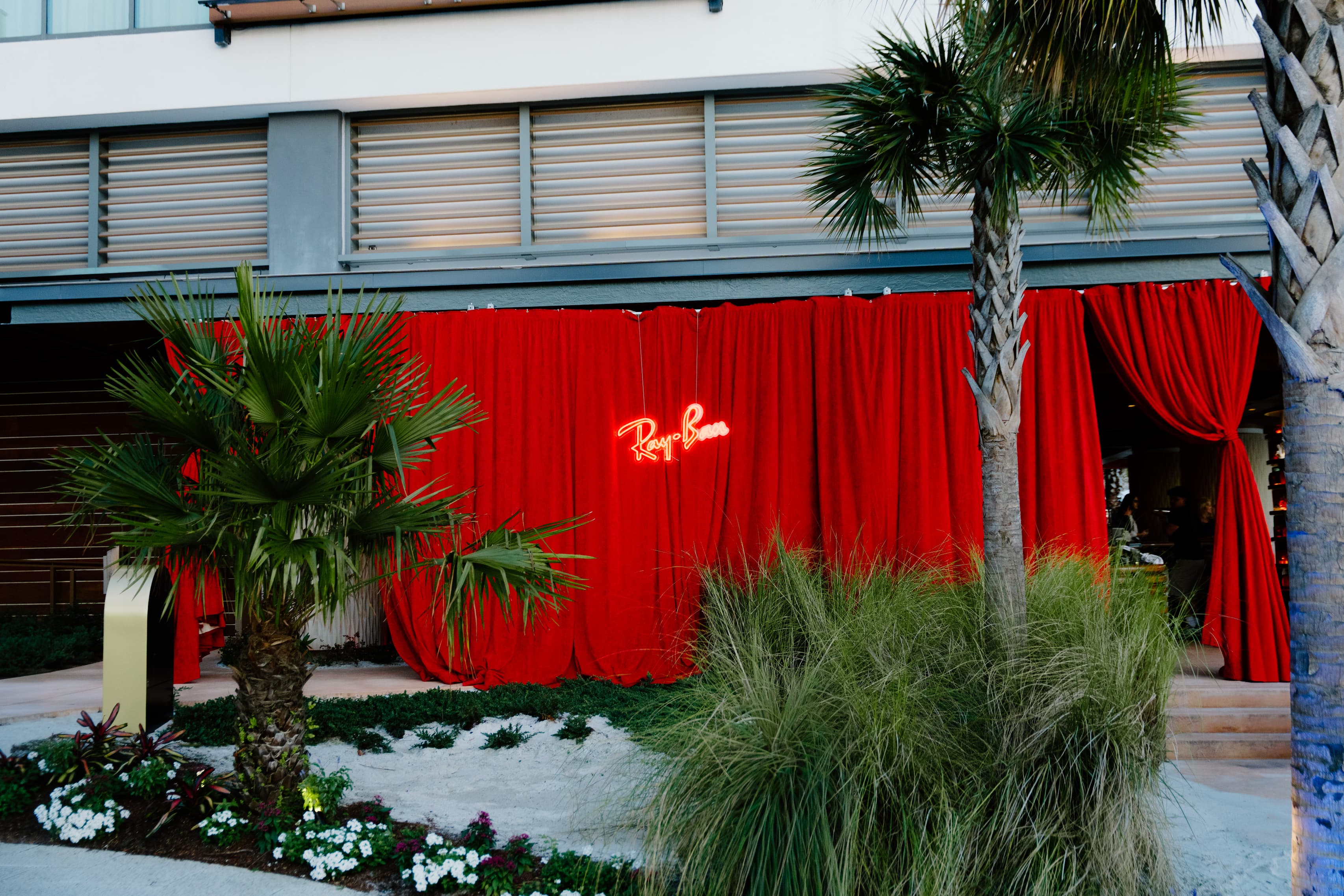 four plinths in metallic with puffer displays holding ray-ban frames beneath red neon sign that says ray-ban