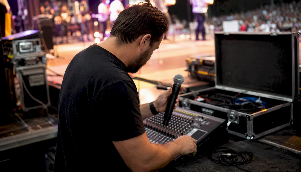 Technician adjusting handheld dynamic mic on stage