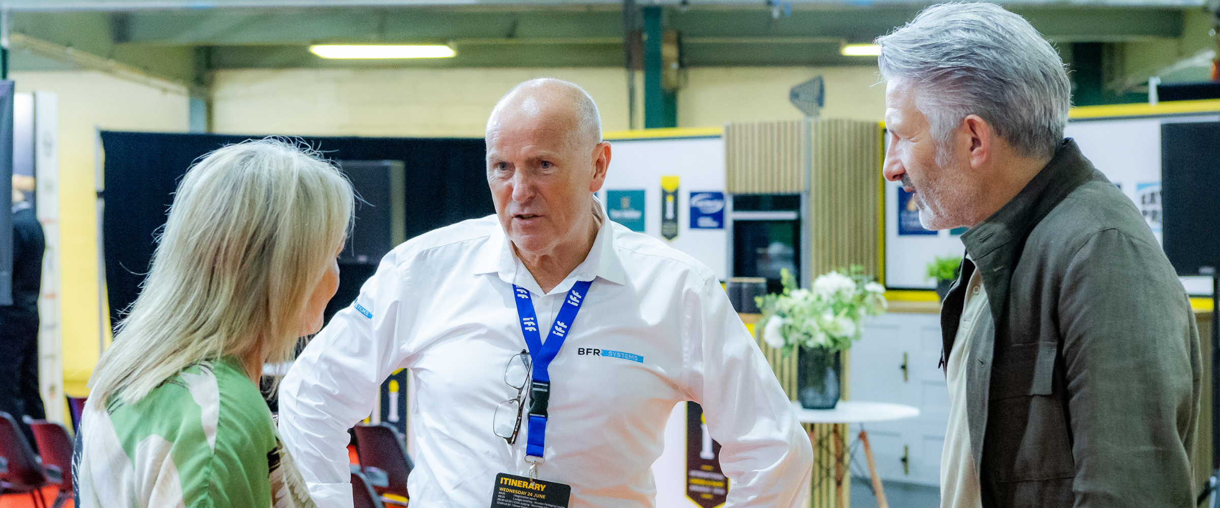 Three delegates in conversation beside an exhibitor stand