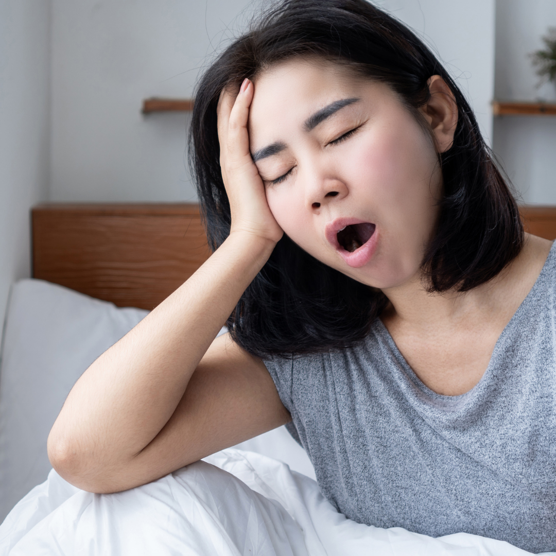 A lady resting head in her hand yawning with eyes closed looking tired