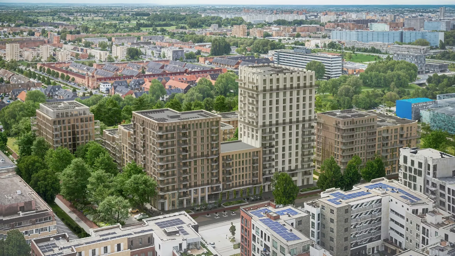 Aerial view of modern residential buildings surrounded by trees in a suburban area with a cityscape in the background.