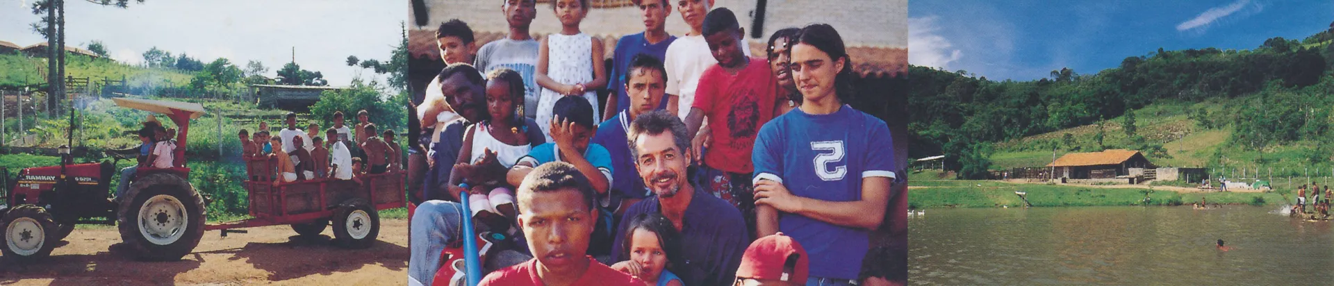 Group of diverse people, including children and adults, gathered outdoors near a tractor and rural landscape with a pond and hills.