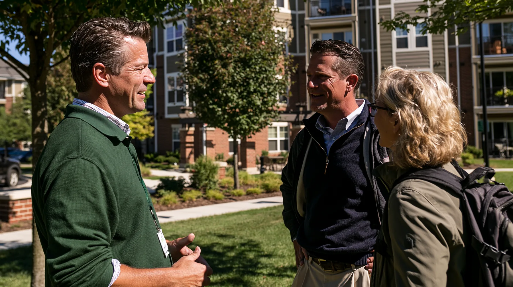 A Union team member in conversation with two people on the lawn of a multifamily property