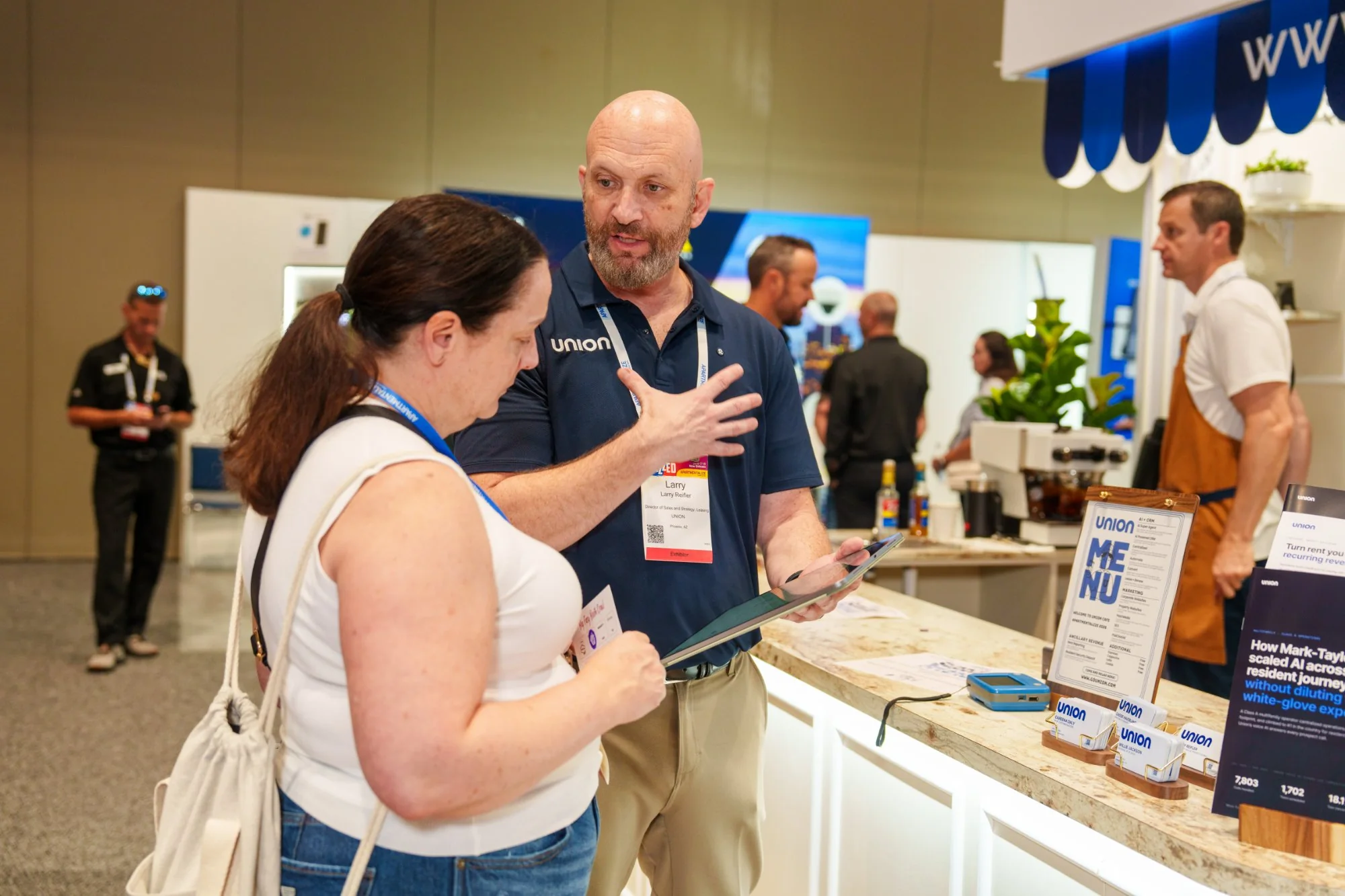 A Union team member walks an attendee through Union on a tablet at the Union booth at Apartmentalize 2026