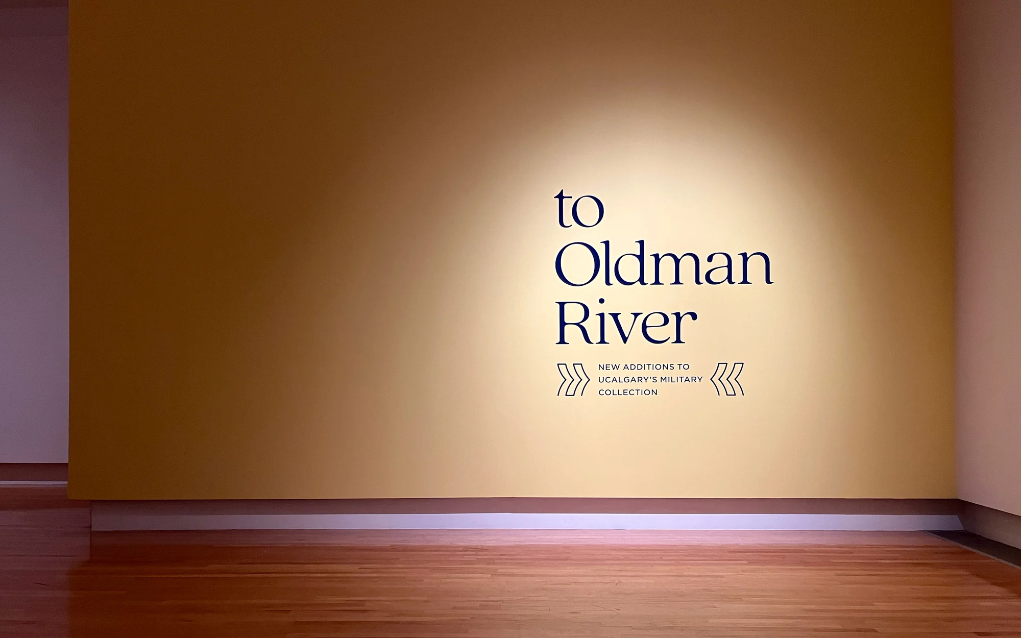 UCalgary Founders' Gallery — exhibition title wall for To Oldman River on yellow background