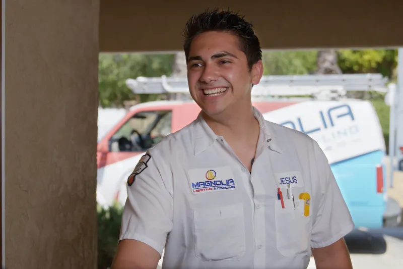 A tech smiling and greeting a customer at their door, a Magnolia truck in the background.