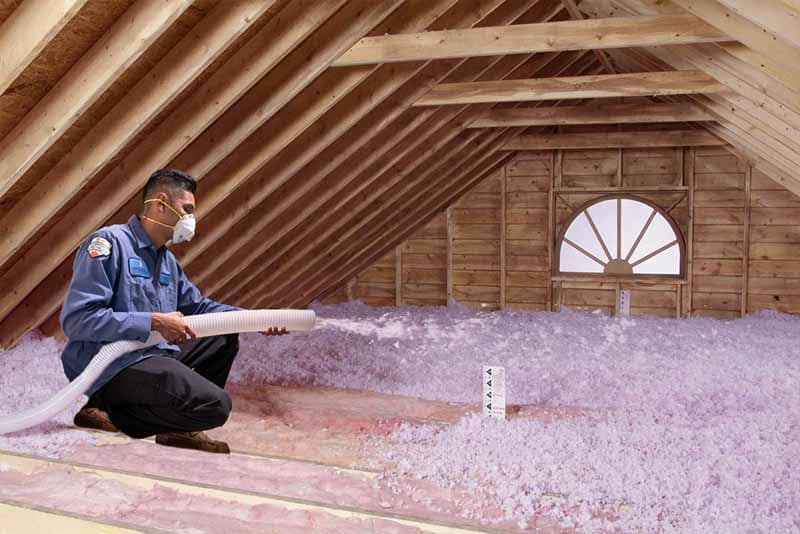 A tech adding insulation into an attic