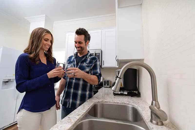 Two customers drinking water from their sink.