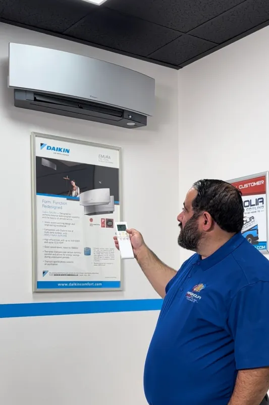 A tech turning on a ductless AC system